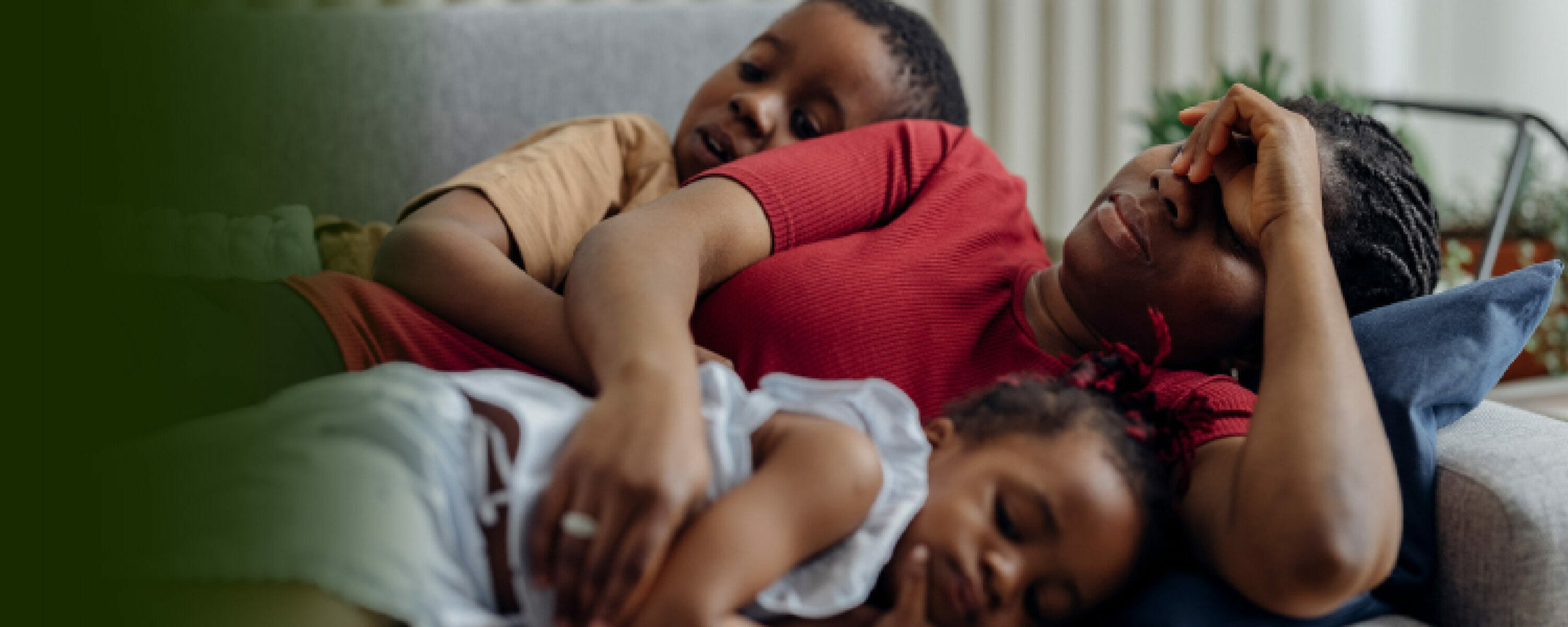 Exhausted woman lying on a couch with her two children