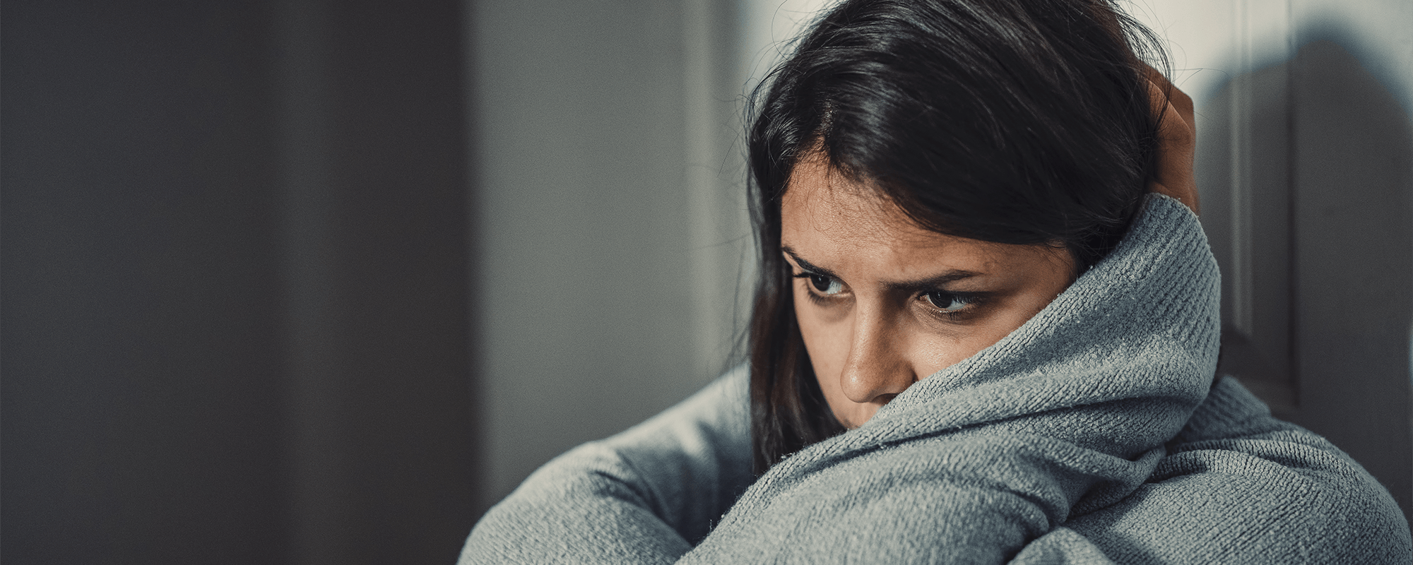 Woman staring into space with hands wrapped around her head